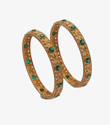 Pair of gold bangles with green gemstones on a white background