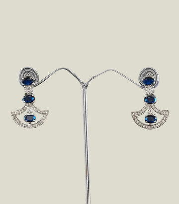 Pair of earrings with blue gemstones and silver setting on a dark background