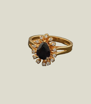 Gold ring with a central black gemstone and smaller diamonds on a gray background