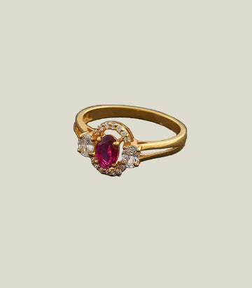 Gold ring with a red gemstone and diamonds on a gray background