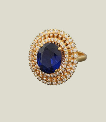 Gold ring with a blue gemstone and diamond accents on a gray background