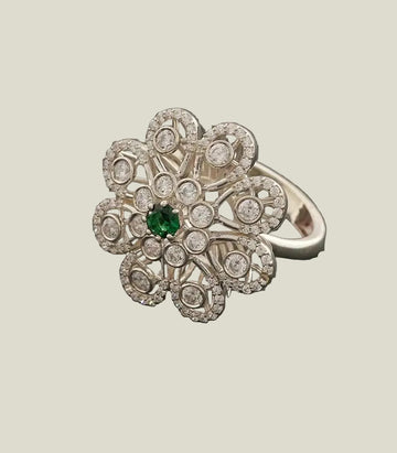 ring with floral design and green gemstone on a dark gray background